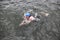 Swimmer in cap and wetsuit performing the breaststroke in dark sea water