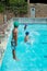 Swimmers jumping in swimming pool at leisure center