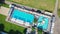 Swimmers of a private outdoor pool. Pool in the middle of the field, cars parked nearby