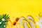 Swimming accessories - orchid flowers, sunblock, heart - shaped glasses, flip flop, palm, shells isolated on yellow background