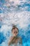 Swimming child jumps underwater in the blue pool with splashes