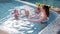 A swimming coach teaches a group of children to swim and dive in an indoor pool.