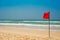 Swimming is dangerous in ocean waves. Red warning flag on beach