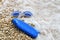 Swimming goggles and suntan lotion lying on pebble beach in water.