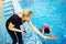 Swimming instructor coach small girl kid, woman hold in hand stopwatch during competitions in pool