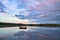 Swimming island in Sweden on a lake at sunset. Clouds reflected in the water