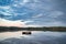 Swimming island in Sweden on a lake at sunset. Clouds reflected in the water