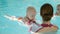 Swimming lesson. Mothers teaching to swim newborn baby at swimming pool