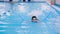 Swimming lessons for children in the pool - beautiful fair-skinned girl swims in the water