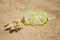 Swimming mask and a piece of yellow coral on a sandy beach. Sport and diving concept