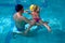 Swimming pool coach teaches a little girl to swim
