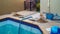Swimming pool drained with tiles removed for repair and piles of building materials an hose to vacuum and other pool maintenance e