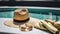 Swimming pool essentials concept. Beach bag with items for safe sunbathing on the deck, sunglasses, straw hat, white blanket and