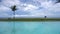 Swimming pool infinity view with blue sky and sea landscape on background, surrounded with palm trees with tropical view