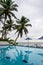 Swimming pool by the ocean, cloudy morning view with palm trees in the background