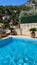 Swimming pool on the rustic style villa. Decorative palms in flower pots. Mountain vie. Water texture on a blue