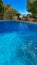 Swimming pool in the rustic style villa. Decorative palms in flower pots. Water texture on a blue background.