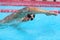 Swimming pool sport man doing crawl swim. Male swimmer with goggles and cap training in stadium for exercise. Cardio