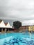 A swimming pool that is very clear sky blue and also a sturdy tree located on the other side of the pool. this photo is suitable a