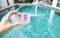Swimming pool water tester in girl hand over blurred pool background