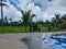 the swimming pool which looks basically fresh blue with views of green rice fields and a bright sky background and white clouds