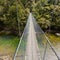 Swing bridge over green jungle river New Zealand