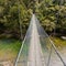 Swing bridge over green jungle river New Zealand