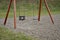 Swing on the playground with chain ropes. The surface around is made of loose pebbles. wooden beam letter A shape