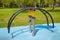 Swing on a yellow metal spring in the form of a curved arc on a playground with a rubberized surface. Kids sports