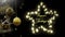 Swinging black and gold christmas baubles with seasons greetings text in star shaped lights on black