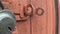 A swinging lock on old wooden doors with a textured background of peeling and scratching paint.