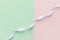 Swirled curly white silk ribbon stretched diagonally on duotone pastel light green pink background. Sewing wedding fashion