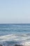 Swirling foam on pebbly beach with open ocean to horizon