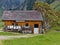 Swiss alpine cheese dairy farm built in old style next to a rock wall empty milk cans in front of the house, german alp cheese