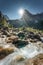 Swiss Alps of Wetterhorn peak with sunburst shine and waterfall flowing in sunny day at Reichenbach, Rosenlaui, Switzerland