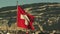 The Swiss Flag flies in front of a mountain in Geneva