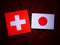 Swiss flag with Japanese flag on a tree stump isolated