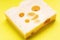 Swiss yellow cheese square chunks with holes on yellow background. Maasdam Dutch cow`s milk cheese