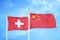 Switzerland and China two flags on flagpoles and blue sky
