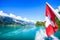Switzerland National Flag at cruise boat`s rear end with beautiful summer view of Swiss natural alps, lake and blue sky background