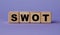 SWOT - acronym on wooden cubes on a lilac background