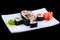 Syake Ikura Maki - Sushi Roll with Fresh Salmon and Cucumber inside on white plate on black background