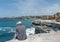 SYDNEY, AUSTRALIA - NOVEMBER 07, 2014: Unidentified Person Sitting on the edge of rock, close to ocean in Sydney, Australia.