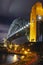 Sydney Harbour Bridge at night, illuminated by lights with long exposure tail lights from a car,