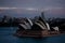 Sydney Opera House a seen from the Harbour Bridge in Australia during sunset with skyscrapers behind