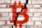 Symbol of bitcoin on the brick wall with big crack in the middle. Bitcoin crash concept