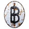 Symbol bitcoin made of forged metal on the background fragment of a metal surface with cracked rust.