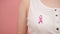 Symbol of breast cancer awareness month, pink october badge on the white shirt of unrecognizable woman