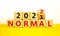 Symbol of covid-19 normal in 2022. Turned a wooden cube and changed words `normal 2021` to `normal 2022`. Beautiful white