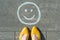 Symbol of happy smiley drawn on the asphalt and woman feet